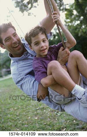 Close-up of a father and son swinging on a rope swing View Large Photo Image Stock Photo - Close-up of a father and son swinging on a rope swing. Fotosearch
