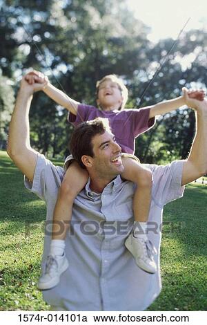 Stock Image - Close-up of a father carrying his son on his shoulders. Fotosearch