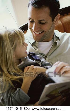 Stock Image - Close-up of a father sitting with his daughter smiling. Fotosearch