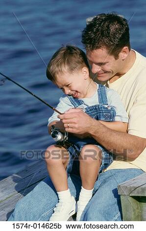 Stock Image - Close-up of a father teaching his son to fish. Fotosearch