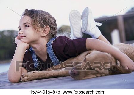 Stock Image - Close-up of a girl lying down with her dog. Fotosearch