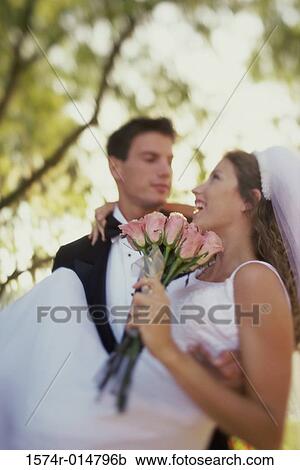 Stock Image - Close-up of a groom carrying his bride. Fotosearch