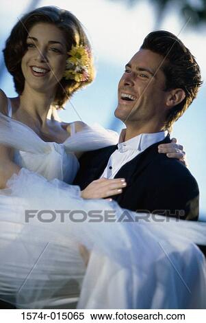Close-up of a groom carrying his bride View Large Photo Image Stock Photography - Close-up of a groom carrying his bride. Fotosearch