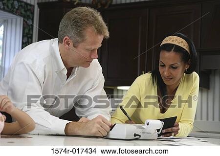 Close-up of a mid adult man looking at a mid adult woman writing with a pen View Large Photo Image Picture - Close-up of a mid adult man looking at a mid adult woman writing with a pen. Fotosearch