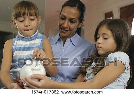 Close-up of a mother looking at her two daughters inserting money into a piggy bank View Large Photo Image Stock Image - Close-up of a mother looking at her two daughters inserting money into a piggy bank. Fotosearch