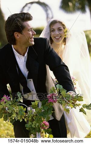 Stock Image - Close-up of a newlywed couple riding a bicycle. Fotosearch