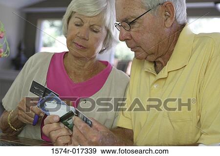 Stock Photo - Close-up of a senior couple destroying credit cards. Fotosearch