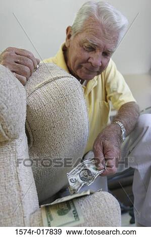 Close-up of a senior man hiding money under a cushion of an armchair View Large Photo Image Stock Photo - Close-up of a senior man hiding money under a cushion of an armchair. Fotosearch