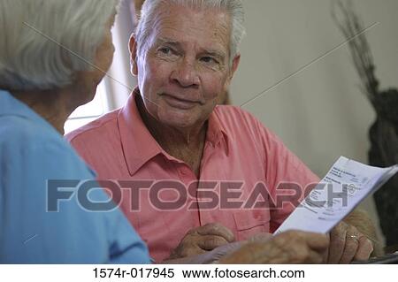 Stock Photography - Close-up of a senior man sitting with a senior woman holding a bill. Fotosearch