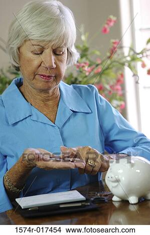 Picture - Close-up of a senior woman counting coins. Fotosearch