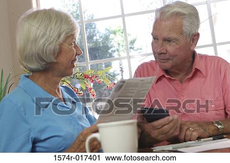 Stock Image - Close-up of a senior woman holding a bill with a senior man sitting beside her. Fotosearch