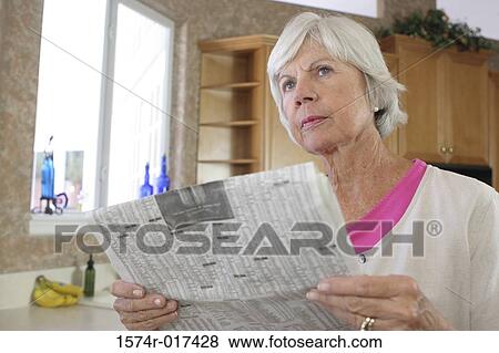 Close-up of a senior woman holding a newspaper View Large Photo Image Stock Photo - Close-up of a senior woman holding a newspaper. Fotosearch