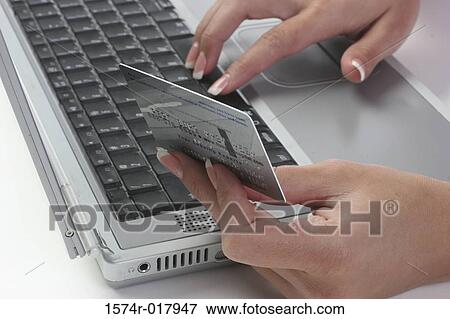 Close-up of a woman's hands using a laptop holding a credit card View Large Photo Image Stock Photo - Close-up of a woman's hands using a laptop holding a credit card. Fotosearch