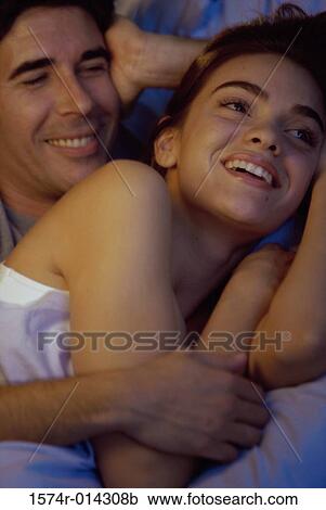 Stock Image - Close-up of a young couple embracing in bed. Fotosearch