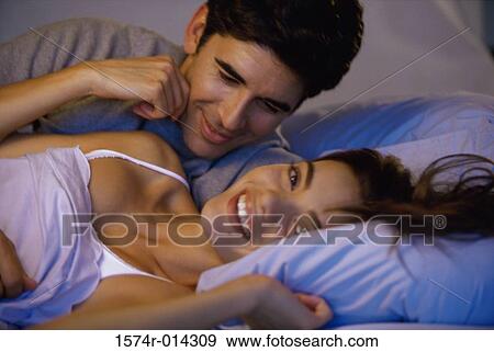 Close-up of a young couple embracing in bed View Large Photo Image Stock Photo - Close-up of a young couple embracing in bed. Fotosearch
