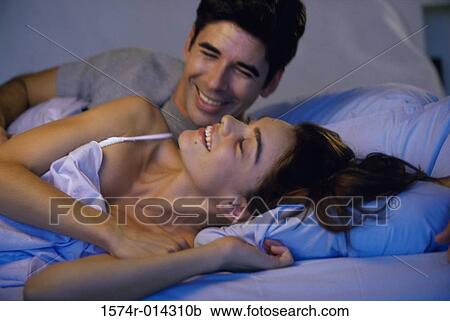 Close-up of a young couple lying in bed smiling View Large Photo Image Stock Image - Close-up of a young couple lying in bed smiling. Fotosearch