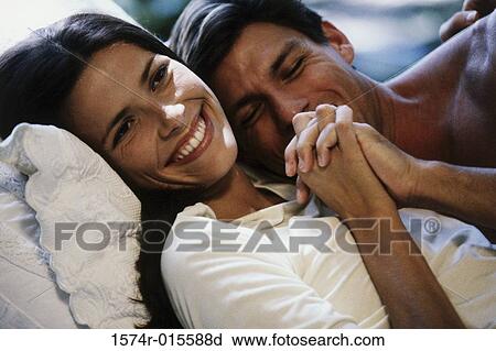 Stock Image - Close-up of a young couple lying on a bed. Fotosearch