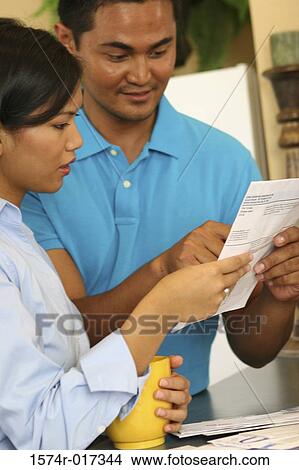 Close-up of a young couple reading a bill View Large Photo Image Picture - Close-up of a young couple reading a bill. Fotosearch