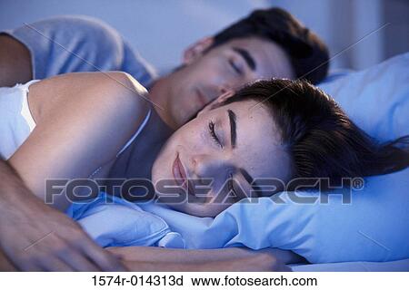Stock Image - Close-up of a young couple sleeping in a bed. Fotosearch
