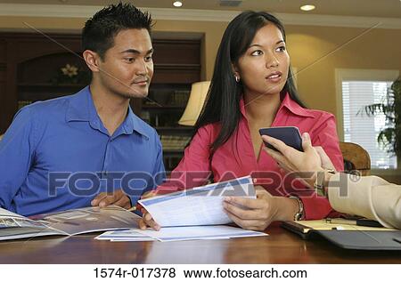Stock Photo - Close-up of a young couple talking to a real estate agent. Fotosearch