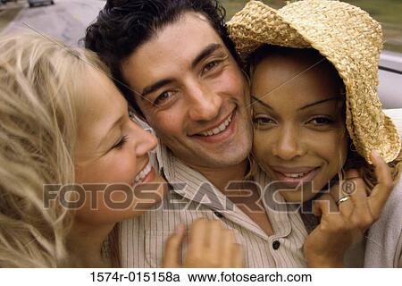 Stock Image - Close-up of a young man and two young women smiling. Fotosearch