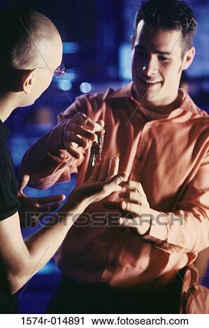 Close-up of a young man giving a car key to his friend View Large Photo Image Stock Image - Close-up of a young man giving a car key to his friend. Fotosearch