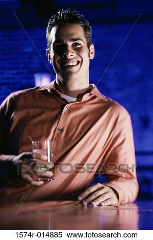 Close-up of a young man holding a drink and smiling View Large Photo Image Stock Photography - Close-up of a young man holding a drink and smiling. Fotosearch
