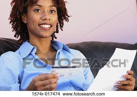 Picture - Close-up of a young woman holding a credit card and a bill. Fotosearch
