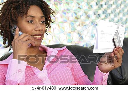 Close-up of a young woman holding a bill using a mobile phone View Large Photo Image Stock Image - Close-up of a young woman holding a bill using a mobile phone. Fotosearch