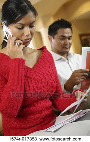 Stock Photo - Close-up of a young woman holding bills talking on a mobile phone. Fotosearch