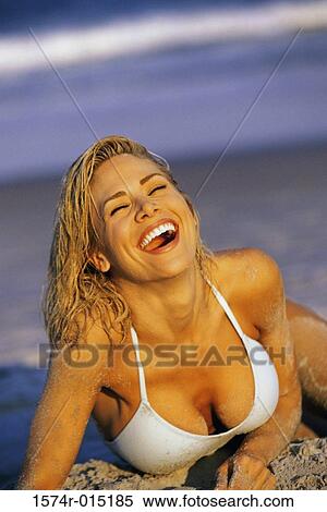 Stock Photography - Close-up of a young woman laughing on the beach with her eyes closed. Fotosearch