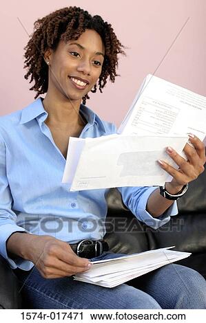 Close-up of a young woman reading bills View Large Photo Image Stock Image - Close-up of a young woman reading bills. Fotosearch