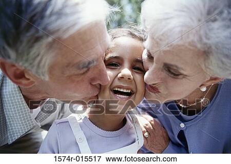 Stock Photo - Close-up of grandparents kissing their granddaughter. Fotosearch