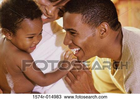 Stock Image - Close-up of parents and their daughter smiling. Fotosearch