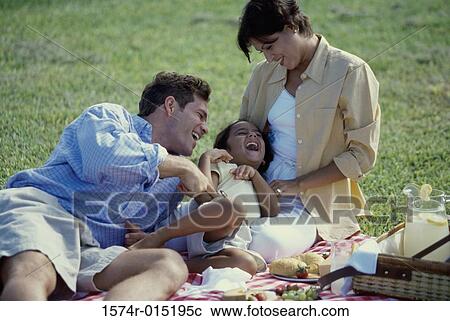 Stock Image - Close-up of parents playing with their daughter in a park. Fotosearch