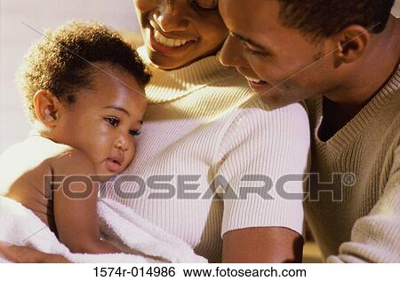 Close-up of parents smiling at their daughter View Large Photo Image Stock Photograph - Close-up of parents smiling at their daughter. Fotosearch