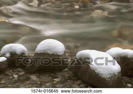 Stock Photography - Close-up of snow on rocks in water. Fotosearch