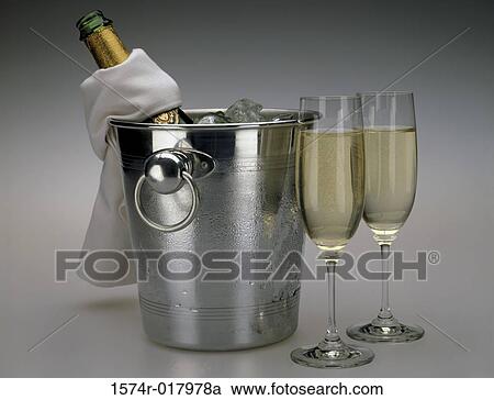 Stock Image - Close-up of two champagne flutes with an ice bucket. Fotosearch