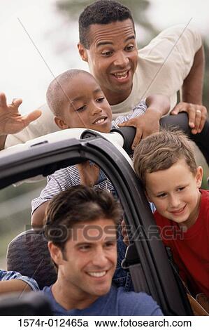 Stock Image - Close-up of two fathers with their sons in a jeep. Fotosearch