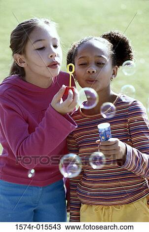 Close-up of two girls blowing bubbles with a bubble wand View Large Photo Image Stock Image - Close-up of two girls blowing bubbles with a bubble wand. Fotosearch