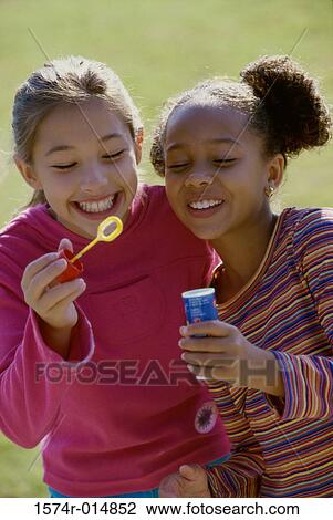 Close-up of two girls holding a bubble wand and smiling View Large Photo Image Stock Image - Close-up of two girls holding a bubble wand and smiling. Fotosearch