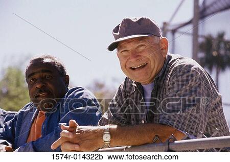 Close-up of two senior men standing against a chain-link fence View Large Photo Image Stock Image - Close-up of two senior men standing against a chain-link fence. Fotosearch