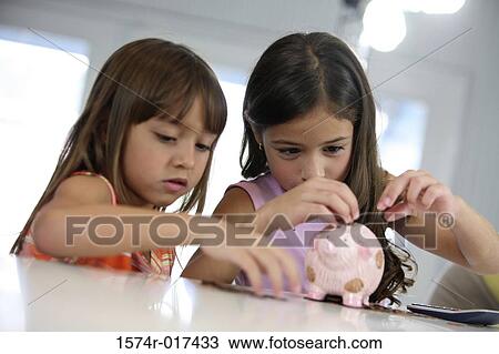 Close-up of two sisters inserting coins into a piggy bank View Large Photo Image Stock Image - Close-up of two sisters inserting coins into a piggy bank. Fotosearch