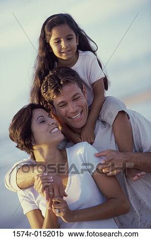 Daughter on her father's shoulders at the beach with her mother standing in front of them View Large Photo Image Stock Image - Daughter on her father's shoulders at the beach with her mother standing in front of them. Fotosearch