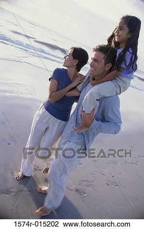 Daughter on her father's shoulders at the beach with her mother standing beside her View Large Photo Image Stock Image - Daughter on her father's shoulders at the beach with her mother standing beside her. Fotosearch