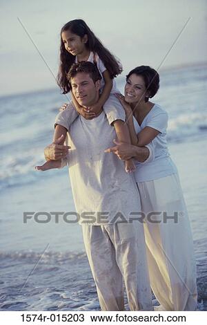 Daughter on her father's shoulders at the beach with her mother standing behind her View Large Photo Image Stock Image - Daughter on her father's shoulders at the beach with her mother standing behind her. Fotosearch
