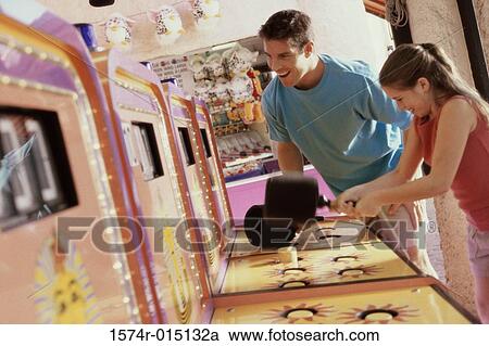 Daughter playing games with her father standing beside her in an amusement park View Large Photo Image Stock Image - Daughter playing games with her father standing beside her in an amusement park. Fotosearch