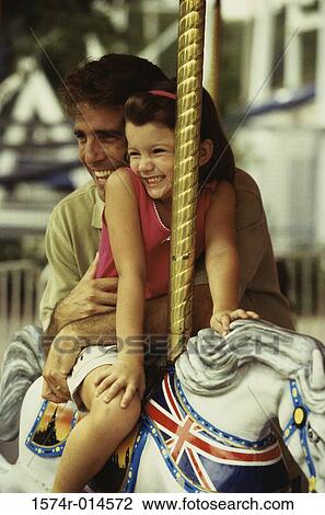 Daughter sitting on a carousel horse with her father standing beside her View Large Photo Image Stock Image - Daughter sitting on a carousel horse with her father standing beside her. Fotosearch