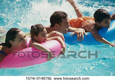 Family relaxing on inflatable rafts in a swimming pool View Large Photo Image Stock Image - Family relaxing on inflatable rafts in a swimming pool. Fotosearch