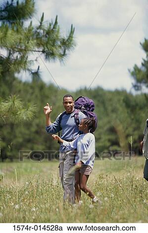 Stock Image - Father and daughter hiking in a field. Fotosearch